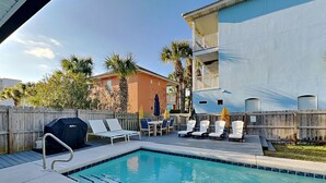 A swimming pool with lounge chairs, a barbecue grill, and a wooden fence. - Coastal Home, Close to Beach with Pool, Golf Cart and Bikes (Miramar Beach)