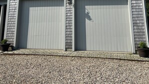 Una casa de una planta con techo a dos aguas y dos puertas de garaje.