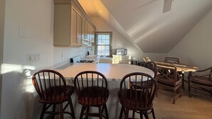 Una cocina con una isla central, sillas de madera y un ventilador de techo.