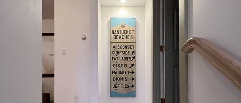 Un escalier avec un panneau indicateur indiquant la direction des plages de Nantucket et d’autres lieux situés à proximité.