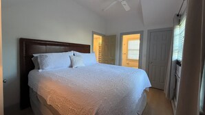 Un dormitorio con una cama grande, un ventilador de techo y una puerta que da a otra habitación.