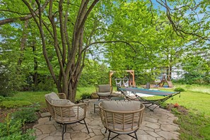 An outdoor patio with wicker furniture, a hammock, and a swing set. - Loft Avec Foyer, Billard, Cinéma Maison et + (Magog)