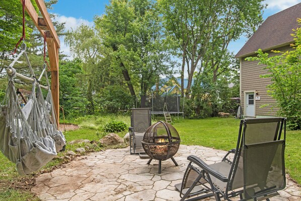 A patio with a fire pit, outdoor seating, and a hammock. - Loft Avec Foyer, Billard, Cinéma Maison et + (Magog)