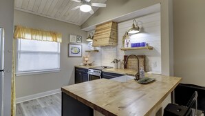 Una cucina con piani di lavoro in legno, una ventola a soffitto e una finestra con persiane.