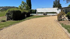 A gravel driveway leading to a building with a pool, surrounded by greenery and hills. - Mas Provençal du XIX Siècle (Cavaillon)