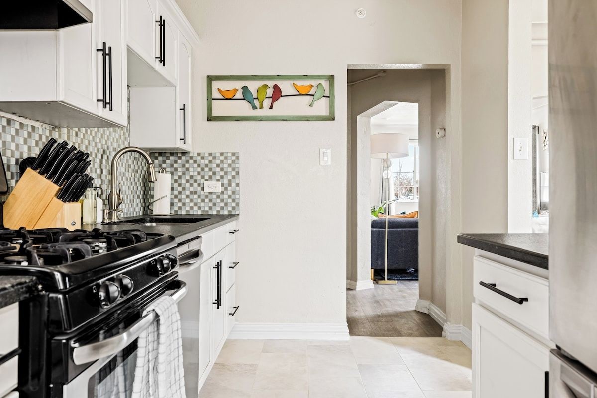 A kitchen with white cabinets, a stove, and a checkered backsplash.