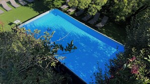A rectangular swimming pool surrounded by lounge chairs and greenery. - Les Aulnes - Two Bedrooms - Five people (Mosnac-Saint-Simeux)