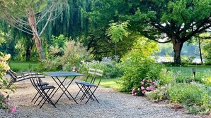 A garden with a table and chairs, surrounded by trees and plants.