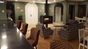 A modern living room with a black bar, brown and plaid sofas, and a fireplace.