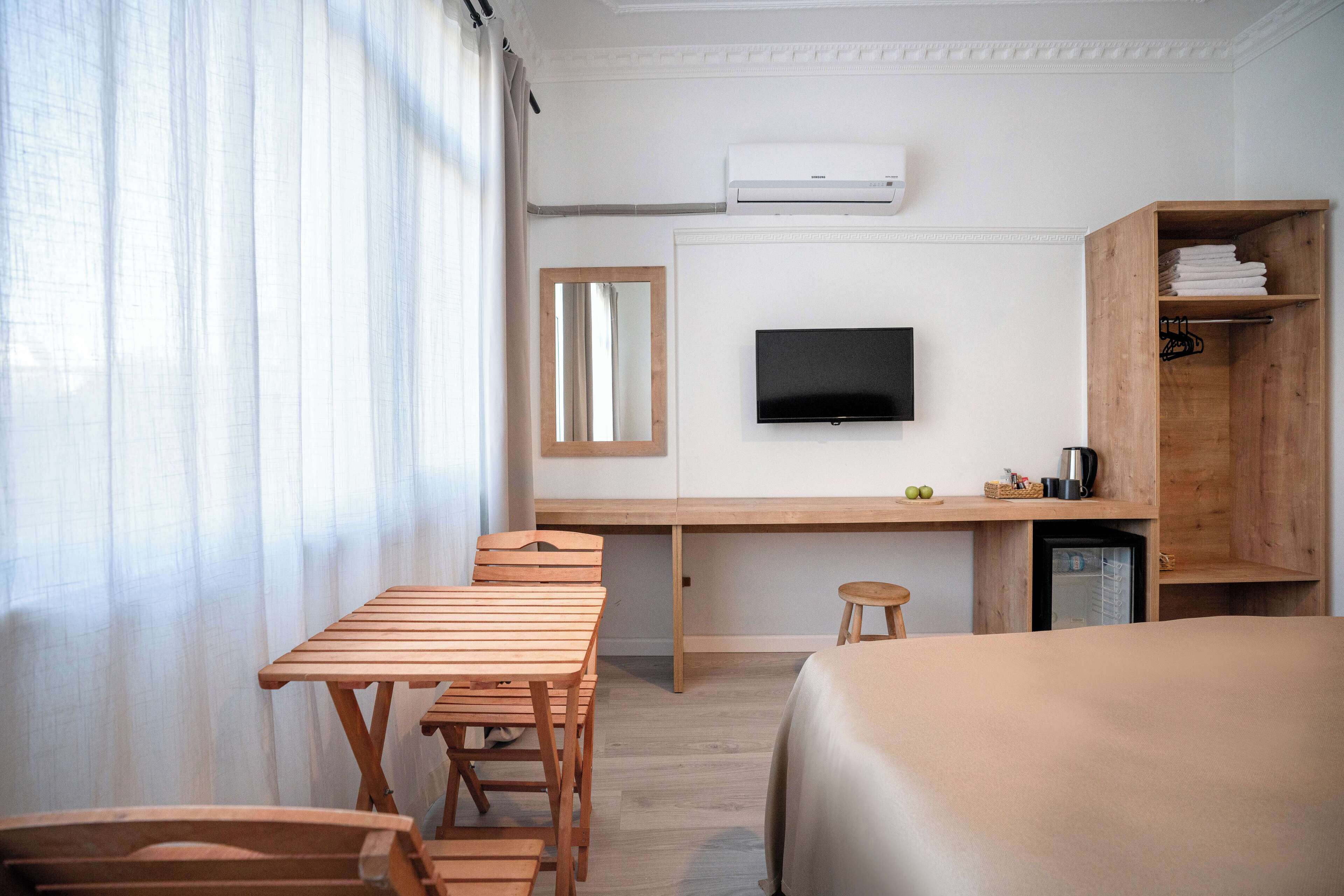 Een hotelkamer met een houten bureau, een televisie, een bed en een kleine koelkast.