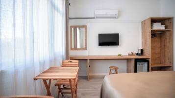 Een hotelkamer met een houten bureau, een televisie, een bed en een kleine koelkast.