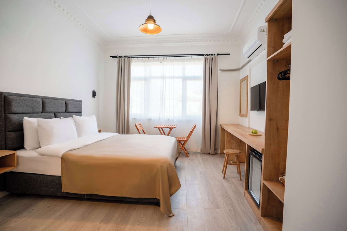 Ein Hotelzimmer mit Bett, Schreibtisch, Stuhl, Fernseher und Klimaanlage.