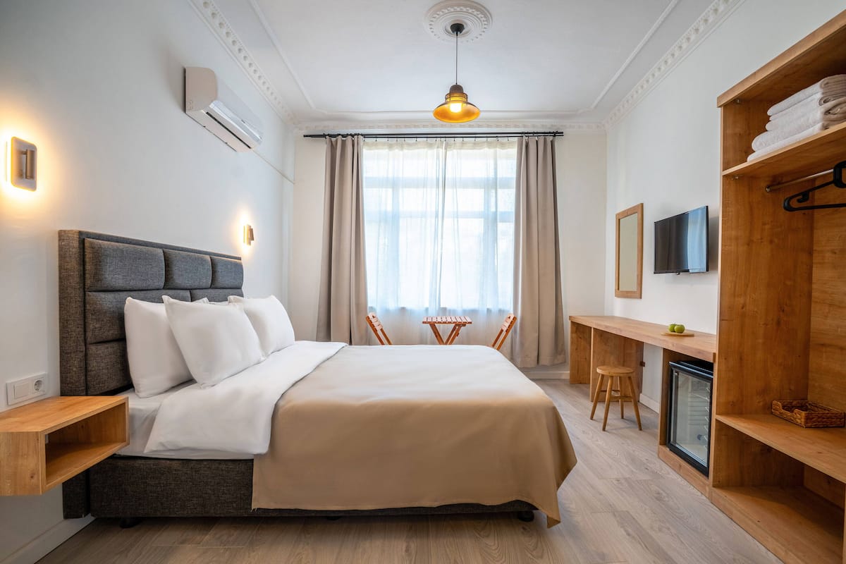 Ein modernes Hotelzimmer mit einem großen Bett, einem Schreibtisch, einem Fernseher und einem Kleiderschrank.