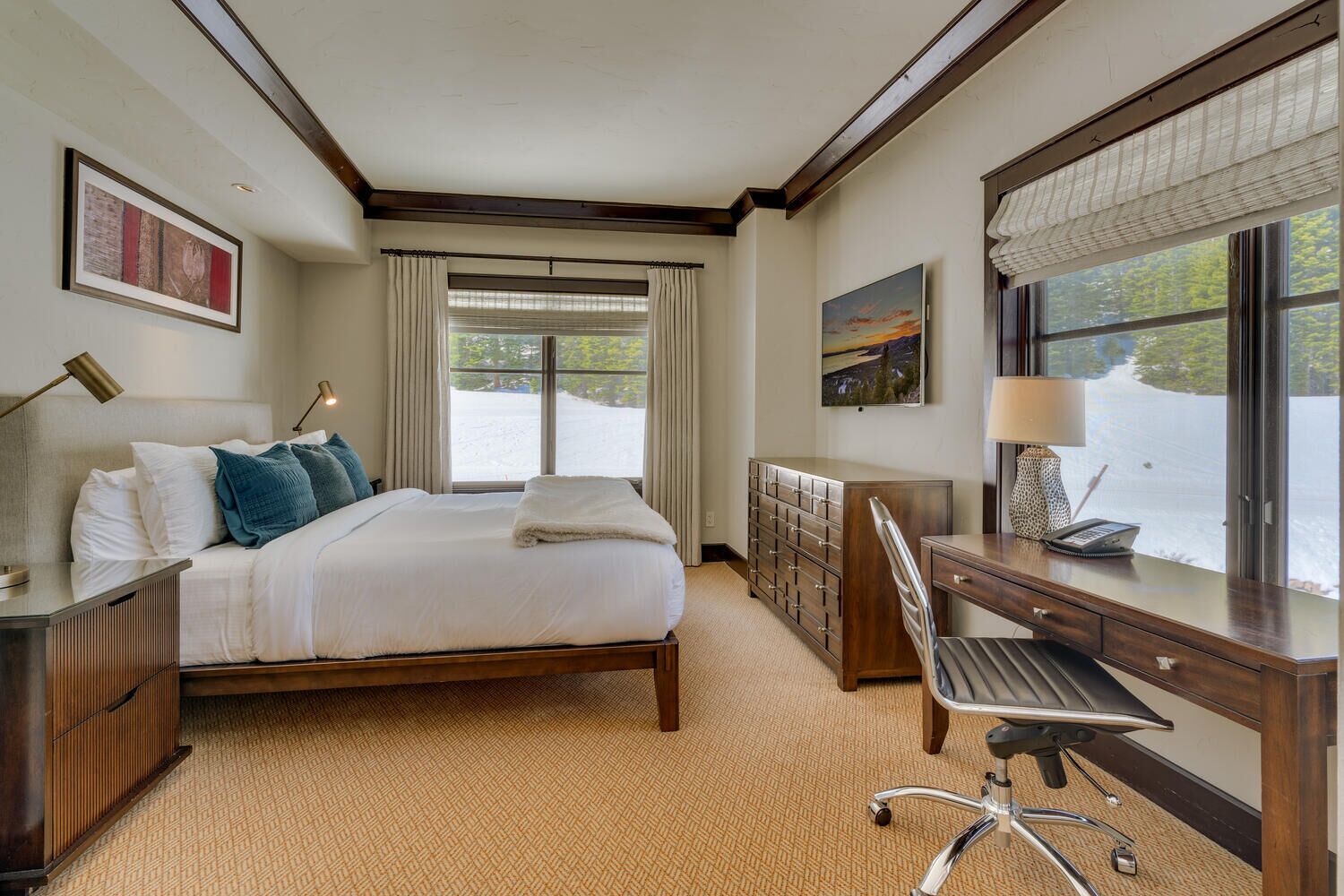 Ein Hotelzimmer mit Bett, Schreibtisch, Stuhl und großen Fenstern.