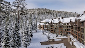 Un complejo turístico cubierto de nieve con varios edificios, una pista de esquí y un bosque denso.