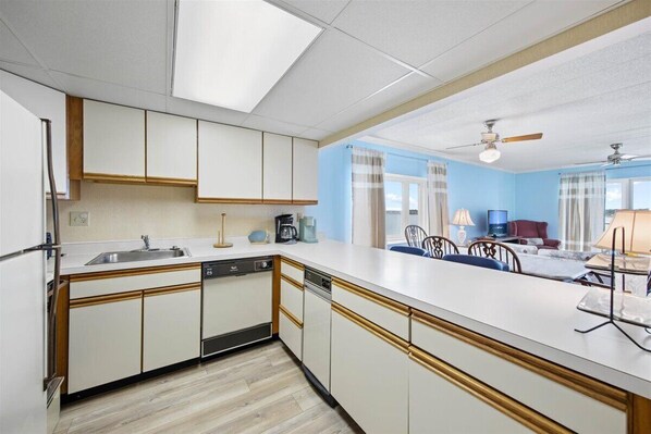 Modern kitchen with central island, sink, and coffee maker, adjacent to a dining area with table and chairs.