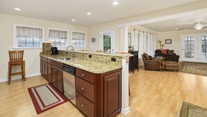 Una cocina amplia con encimeras de granito, armarios de madera y lavavajillas integrado.