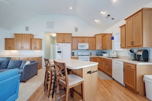 Una cocina moderna con armarios de madera, una isla central y un comedor con sillas.