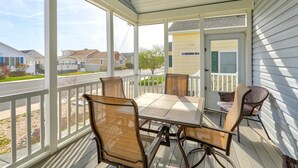 Une véranda abritée avec une table et des chaises, une vue sur la rue et une maison en arrière-plan.
