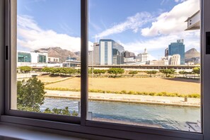 A view through a window of a cityscape with modern buildings, a river, and a park area.