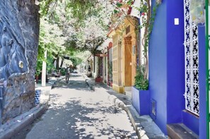 A narrow street with buildings on either side, some with balconies and decorative elements.