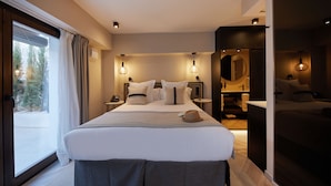 Habitación de hotel moderna con una cama grande, mesitas de noche, un espejo y vistas a un paisaje nevado a través de la ventana.