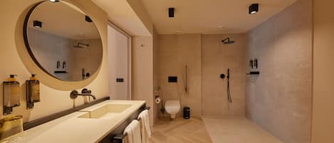 A modern bathroom with a large mirror, dual sinks, a shower, and a toilet.