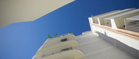 Un edificio moderno con varios balcones y un cielo azul despejado.