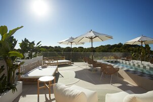 Una piscina al aire libre, sombrillas, sillones reclinables de piscina