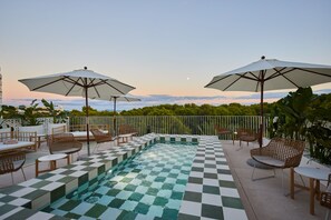 A checkered pool area with lounge chairs and umbrellas, surrounded by a white fence and greenery. -  Belle Marivent Boutique Hotel (Palma de Mallorca)