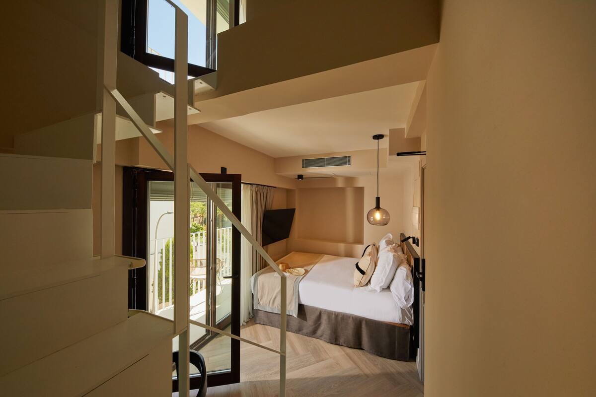 Ein modernes Hotelzimmer mit einem großen Bett, einem Fernseher und einem Balkon mit Blick.