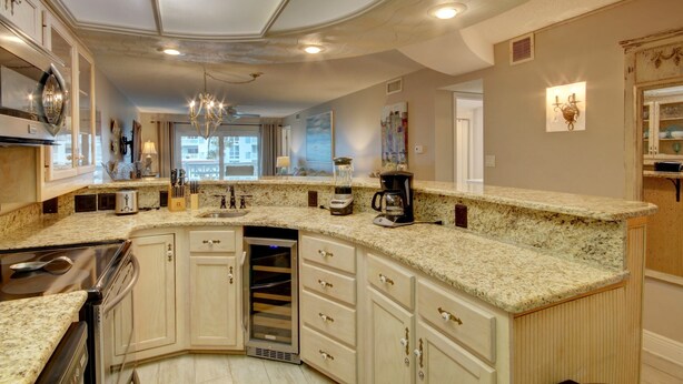 A spacious kitchen with granite countertops, a built-in oven, and a wine cooler.