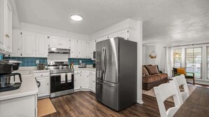 Una cocina moderna con armarios blancos, electrodomésticos de acero inoxidable y un refrigerador grande.