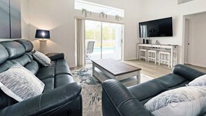Ein modernes Wohnzimmer mit einer Ledersofa, einem Couchtisch und einem an der Wand montierten Fernseher.