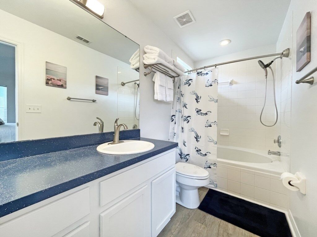 A modern bathroom with a large mirror, a sink, a toilet, and a shower.