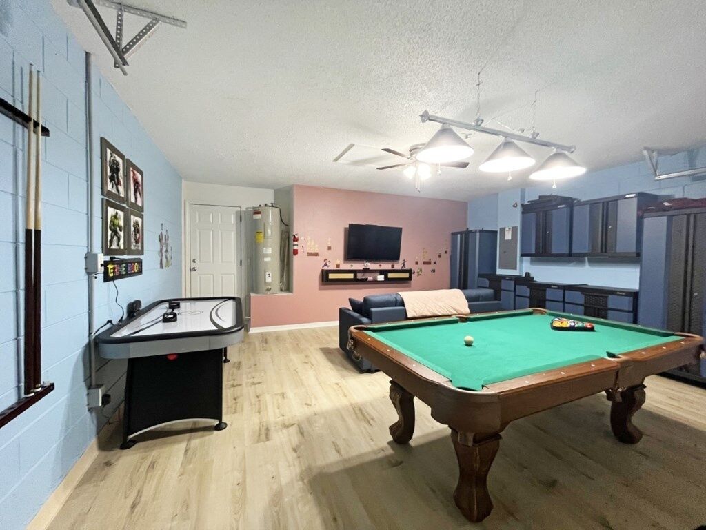 Una habitación con mesa de billar, un sofá, televisión y armarios.