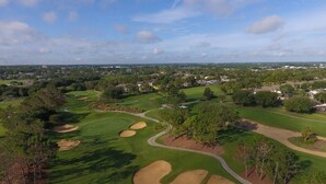 Um campo de golfe com bunkers de areia, árvores e céu limpo.