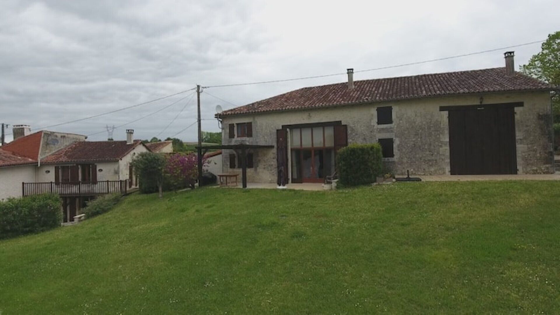 Uma casa de dois andares com telhado de telhas, garagem e pequeno jardim frontal.