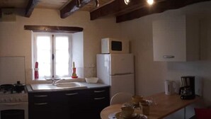 A compact kitchen with a central island, a stove, a refrigerator, and a window with natural light. - Le Calme, a cozy studio for two. (Nanteuil Auriac de Bourzac)