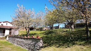 A rustic house with a stone wall, a small porch, and a garden with trees and grass. - Le Calme, a cozy studio for two. (Nanteuil Auriac de Bourzac)