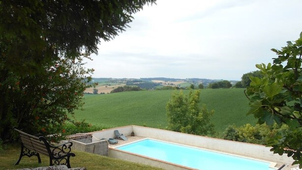 A swimming pool with a view of a green field and a bench. - Le Calme, a cozy studio for two. (Nanteuil Auriac de Bourzac)
