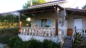 A rustic house with a stone facade, a wooden balcony, and a small garden area. - Le Calme, a cozy studio for two. (Nanteuil Auriac de Bourzac)