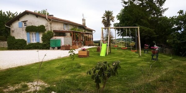 Ein Haus mit Garten, inklusive Schaukel und Rutsche.