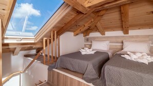 A cozy attic bedroom with two beds, wooden beams, and a skylight. - Claudio Stone House!! (Zakynthos)