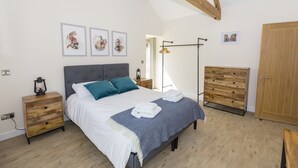 Une chambre à coucher avec un lit, des tables de chevet, une commode et des œuvres d’art accrochées au mur.