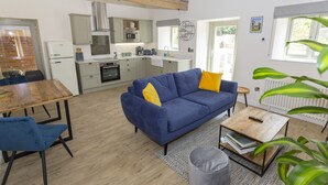 Un salon moderne avec un canapé bleu, une table basse en bois et un coin repas comprenant une table en bois et des chaises bleues.