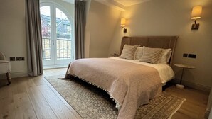 Ein Schlafzimmer mit einem großen Bett, einem Fenster mit Blick und einem Nachttisch mit Lampe.