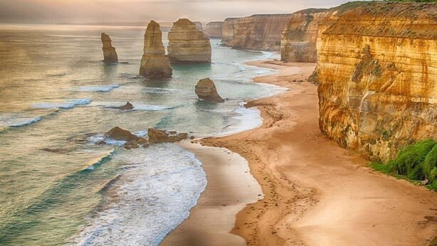 A coastal landscape with prominent rock formations and a sandy beach.