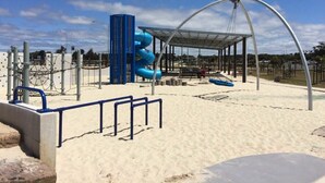 A playground with a slide, climbing structures, and a covered seating area.