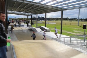 Een skatepark buiten met hellingen en een overdekt zitgedeelte.